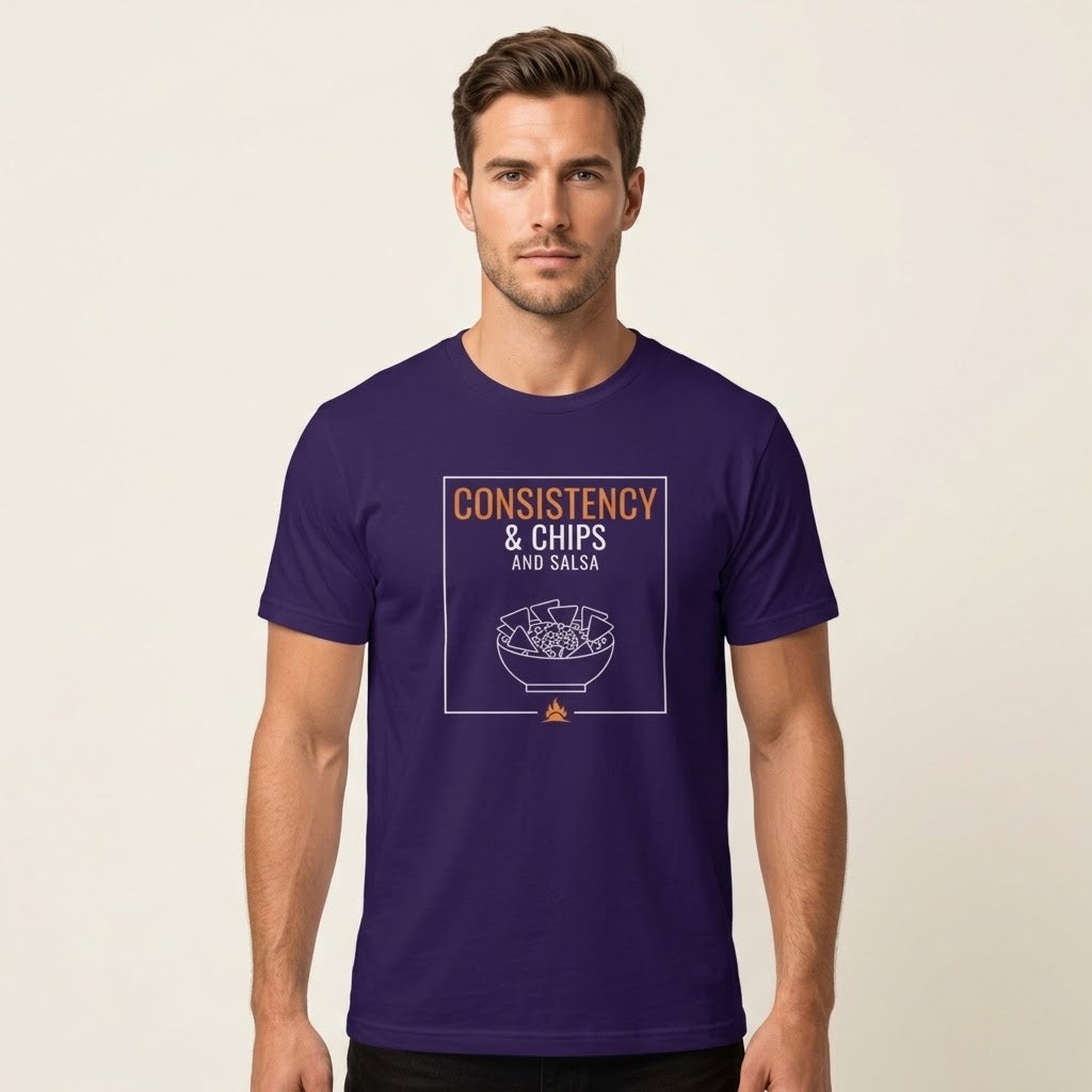 A man wearing a dark purple t-shirt with a graphic print that reads 'CONSISTENCY & CHIPS AND SALSA' above a bowl illustration, set against a plain light beige background.