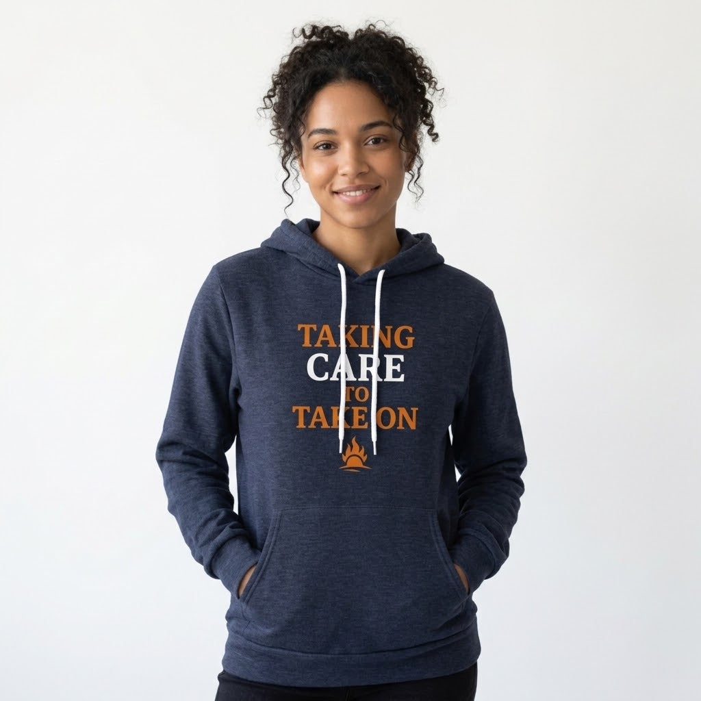 A woman with curly dark hair wearing a navy blue hoodie with the text 'TAKING CARE TO TAKE ON' in orange and white, standing against a plain white background.
