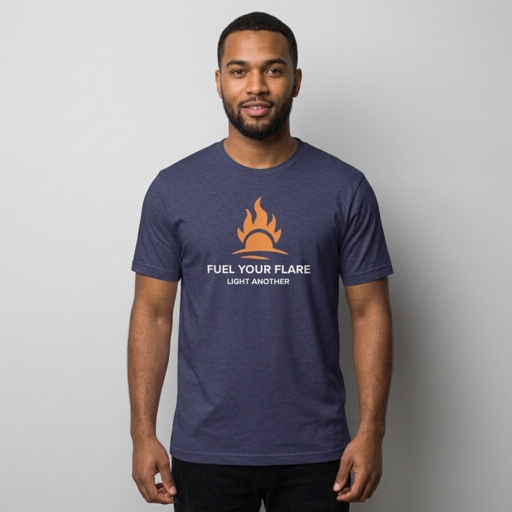 A man wearing a heather navy blue t-shirt with a graphic of a yellow and orange flame and the text 'FUEL YOUR FLARE' and 'LIGHT ANOTHER' printed on the chest, set against a plain light gray background.